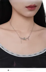 Detail of S925 silver necklace with cat on branch pendant and tassel on female model neck