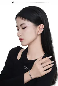 Silver jewelry set with black details including ear cuffs and rings on a female model