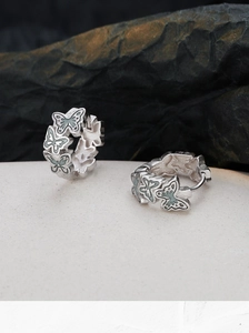 Macro shot of S925 sterling silver hoop earrings with blue enamel butterfly relief details
