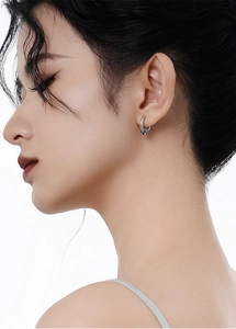Detail of vintage sterling silver hoop earrings with intricate texture and star zircon