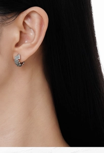 Macro detail of silver sterling butterfly hoop earring with matte finish on ear