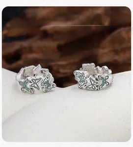 Macro detail of S925 silver hoop earrings with vintage green enamel butterfly charms