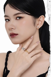 Close-up of a silver star earring and layered rings on a model with minimalist jewelry style