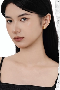 Gros plan de boucles d'oreilles gouttes dorées minimalistes portées par un mannequin