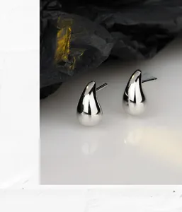 Vue macro des boucles d'oreilles minimalistes en argent 925 en forme de goutte d'eau polie