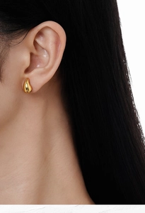 Gros plan d'une boucle d'oreille goutte en or minimaliste sur le mannequin