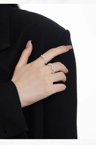 Detail of S925 silver chain rings with white pearl inlay worn on hand with chic black suit