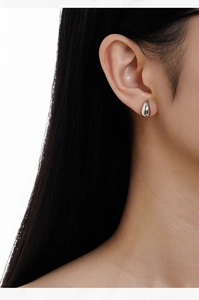Gros plan de boucles d'oreilles gouttes d'eau en argent S925 portées par un mannequin