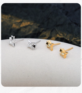 Macro shot of silver and gold S925 star studs with zircon and black enamel details