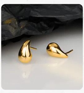 Détail macro de boucles d'oreilles gouttes dorées polies avec surface réfléchissante
