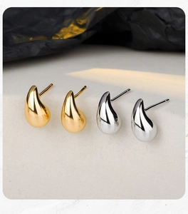 Gros plan de boucles d'oreilles gouttes minimalistes or et argent sur pierre