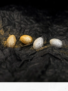 Macro shot of gold and silver pave teardrop earrings on black textured fabric