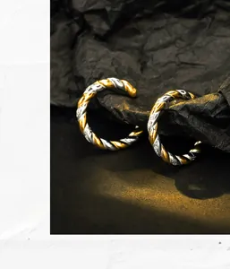 Macro detail of intertwined gold and silver twisted rope earrings with high-polish metallic finish