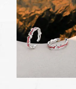 Macro detail of irregular silver rings with glossy red enamel on stone background