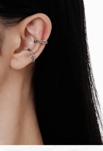 Detailed view of silver wave ear cuffs with pink enamel on the model's ear cartilage