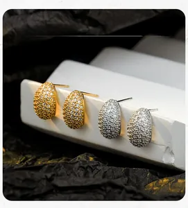 Macro view of teardrop stud earrings with pave diamond setting in gold and silver