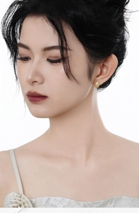 Close-up of golden oval stud earrings with fine textured mesh pattern on female model