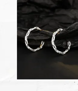 Macro detail of S925 sterling silver hoop earrings with chain link texture design