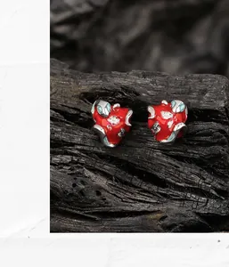 Detailed macro view of red enamel heart earrings with silver frames and sparkling crystals