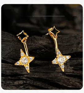 Macro detail of gold-plated star earrings with white zircon and black star motifs