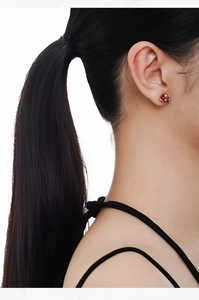 Close-up of snake and apple stud earrings with red enamel on a model's ear