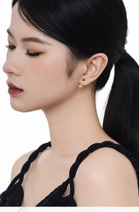 Close-up of a model wearing a delicate gold star stud earring with a sparkling zircon