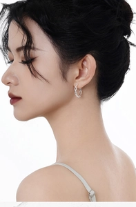 Macro close-up of a minimalist silver chain link hoop earring on model side profile