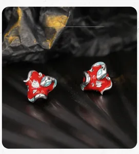 Macro detail of red enamel apple stud earring with silver snake and white crystals
