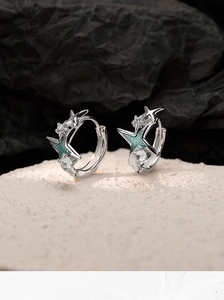 Détail de boucles d'oreilles étoile en émail bleu avec zircons et finition argentée