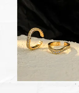 Macro detail of wave-shaped S925 sterling silver gold ear cuff with shimmering cubic zirconia
