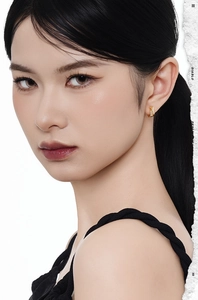 Close-up of small gold hoop earrings with pavé stones on a model's earlobe