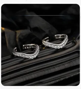 Macro detail of V-shaped silver ear cuffs with pavé-set shimmering clear zircon stones