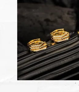Macro detail of geometric gold hoop earrings with multi-layer rows of inset diamonds