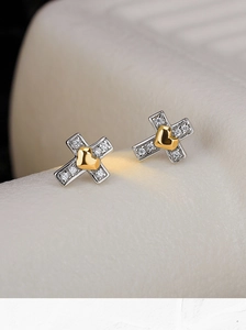 Vue macro de boucles d'oreilles croix en argent S925 avec zircon et coeur doré