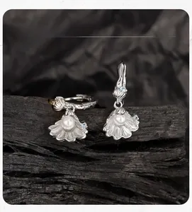 Macro detail of S925 silver seashell drop earrings with pearls and blue cubic zirconia
