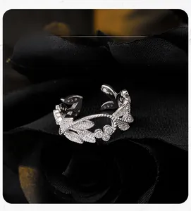 Macro shot of silver leaf ring with pavé-set zircons on black textured background