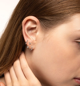 Detail of 925 sterling silver hoop and bead stud earrings worn on a model's ear