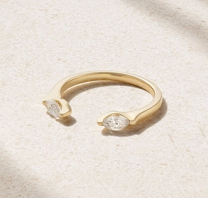 Detail of gold open ring with dual marquise-cut zircons on a textured stone background