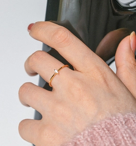 Detail of a gold marquise-cut zircon ring worn by a model with a pink knit sweater