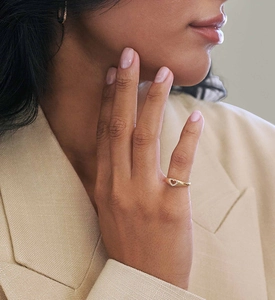 Close-up of a gold heart-shaped signet ring with micro-inlaid zircon on a model