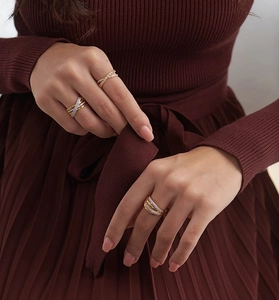 Detail of layered gold ring with micro-set zircons worn by model in red sweater