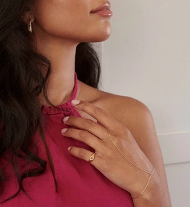 Detailed close-up of a hollow heart ring with diamonds and matching gold hand harness