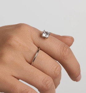 Macro shot of silver adjustable S-ring featuring square-cut sparkling zircon on finger