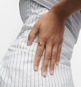 Close-up of a minimalist golden adjustable open ring with a sleek ball design on model finger
