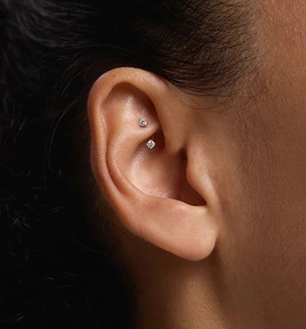 Macro view of S925 silver curved barbell stud featuring round zircon stones on a rook piercing