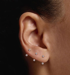 Macro shot of six prong-set clear round zircon stud earrings worn on ear lobe