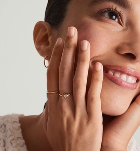 Close-up of a gold S925 silver star ring set with zircon on a model's hand and ear