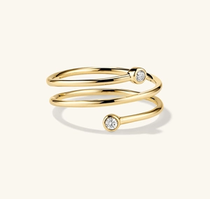 Detailed close-up of a spiral gold ring featuring two sparkling round-cut zircon stones