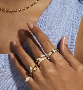 Close-up of stacked gold water drop zircon rings and link chain necklace on model