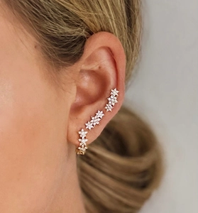 Gros plan de boucles d'oreilles fleurs dorées et bagues d'oreilles avec cristaux brillants